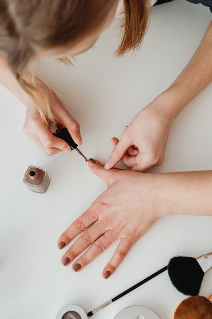 Top view of a professional manicure session showing nail polish application on nails with cosmetic tools.